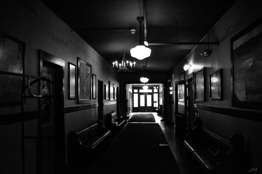 Dark hallway with dim lighting creates an eerie atmosphere with exit sign visible.