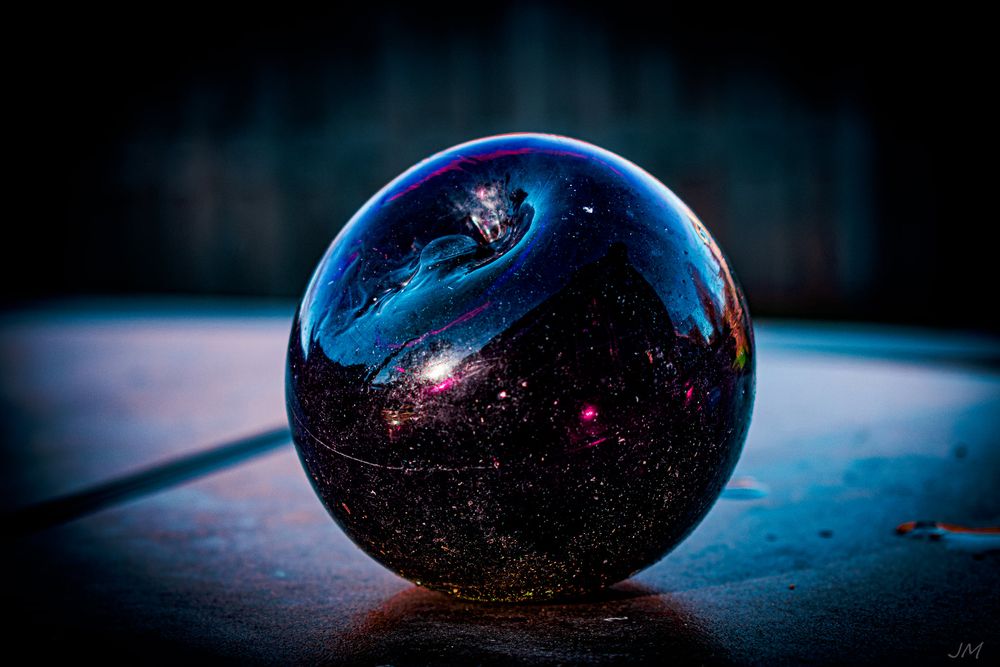 A crystal ball reflects mystical cosmic patterns and lights against a dark background.