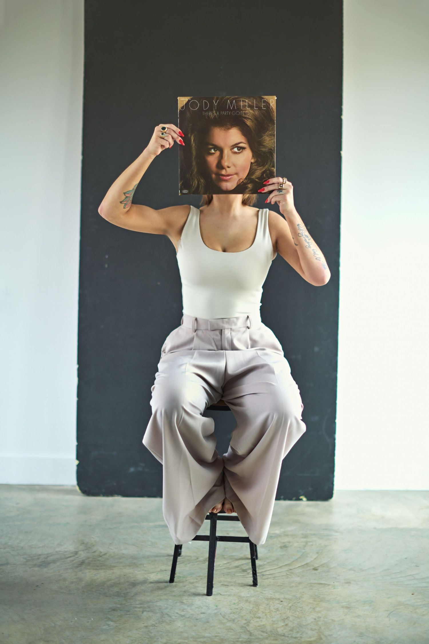 Modern portrait series showing someone in white clothing posing on a chair against a dark wall.