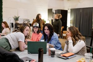 EMPW women's networking community in Puyallup, WA group of women sitting at table over laptop talking business learning supporting each othe