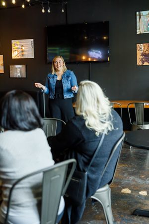Eastside Entrepreneurs women business owner networking group in Redmond, WA woman standing in front presenting her elevator pitch to group