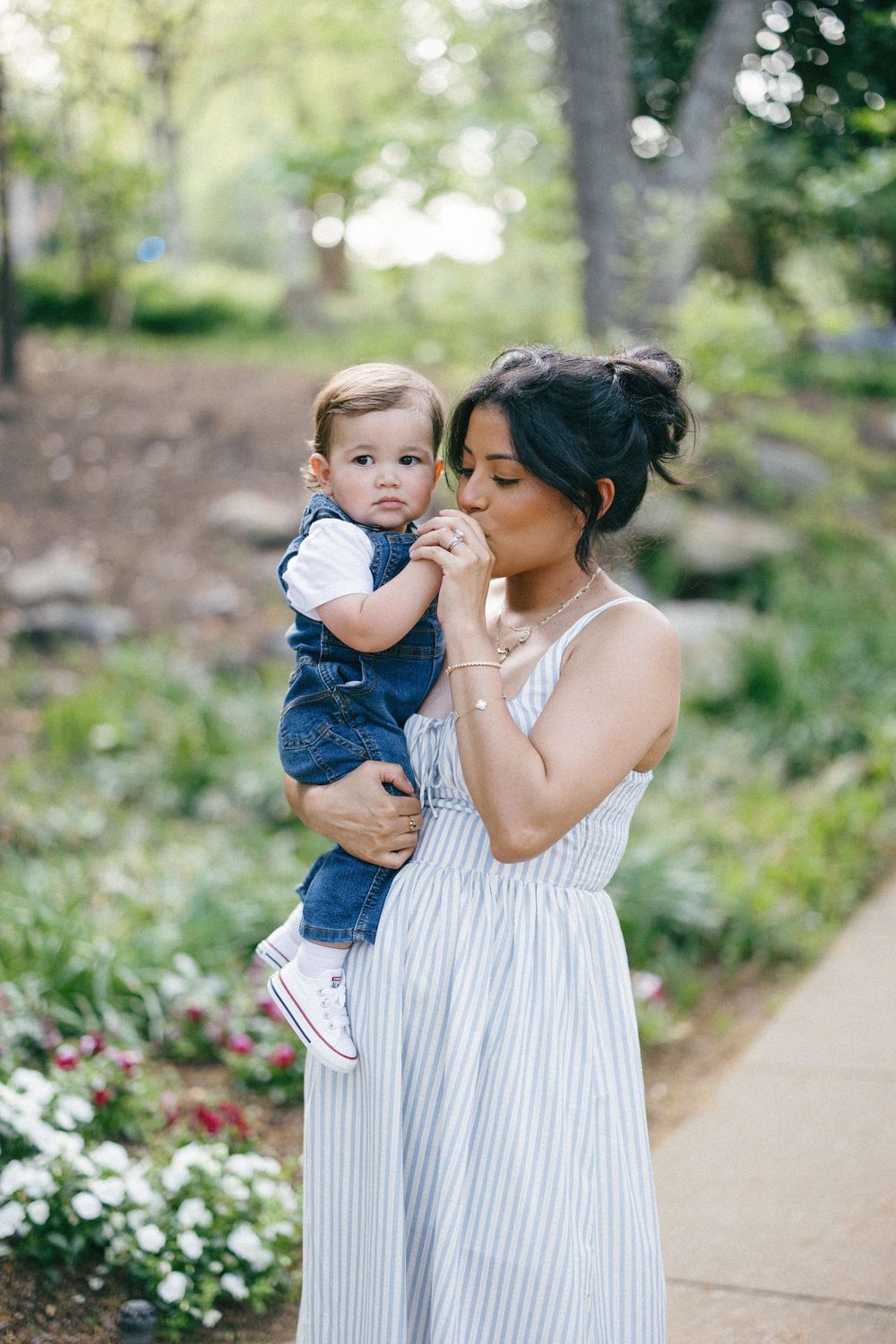 A tender family moment captured outdoors with coordinated blue and white outfits on a garden path.