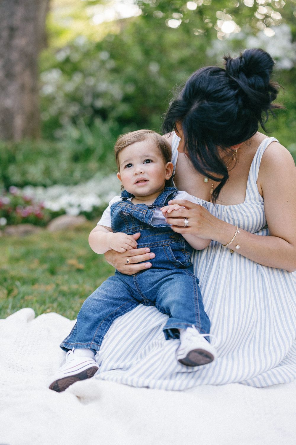 Sweet candid moments shared while resting on a white blanket in an outdoor setting.