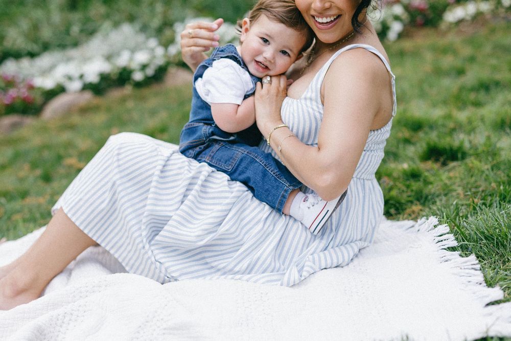 Candid outdoor photos in a grassy field with white daisies while wearing casual blue and white striped attire.