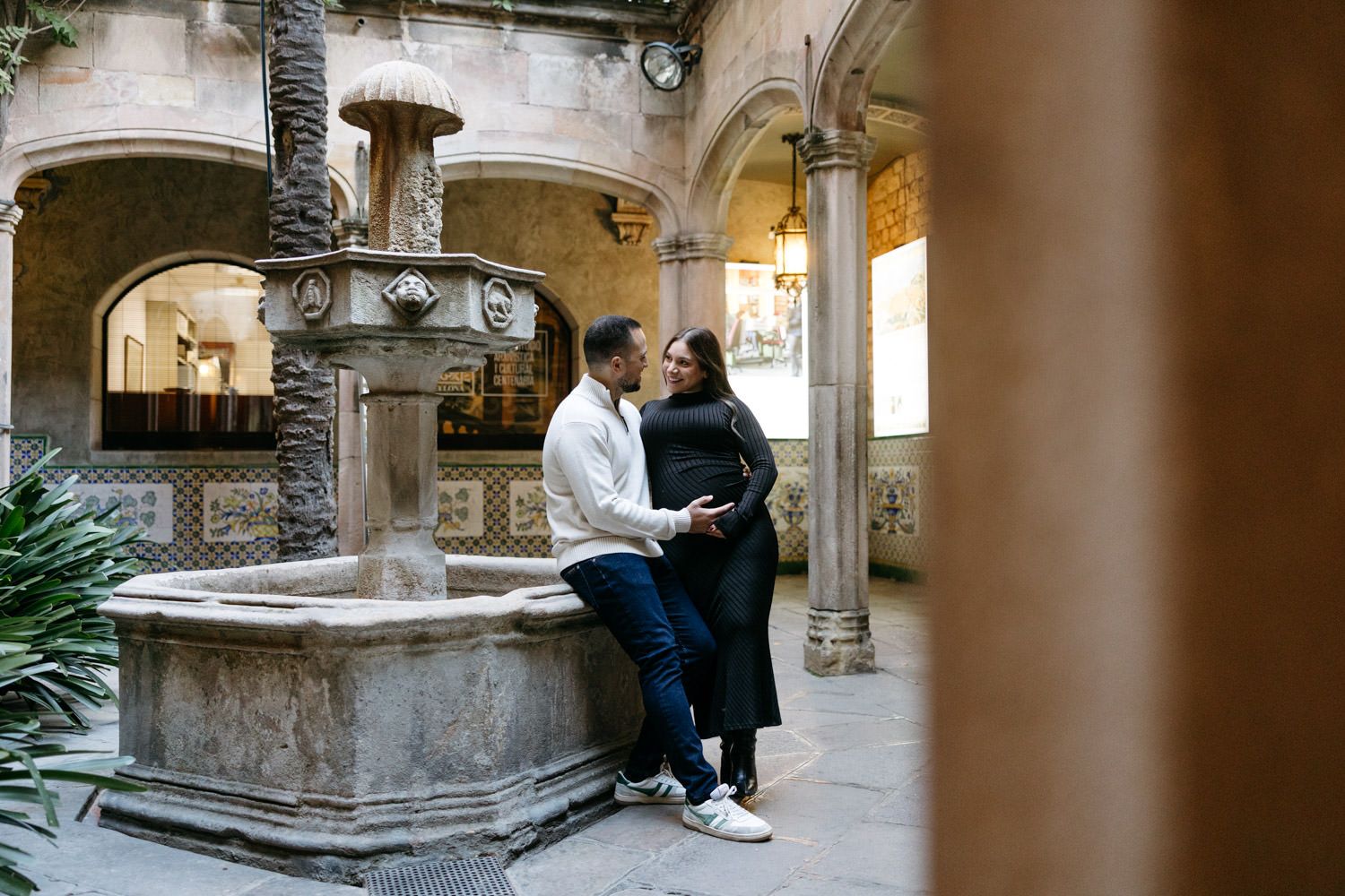 Couple sits together in a historic stone cloister with arched columns.