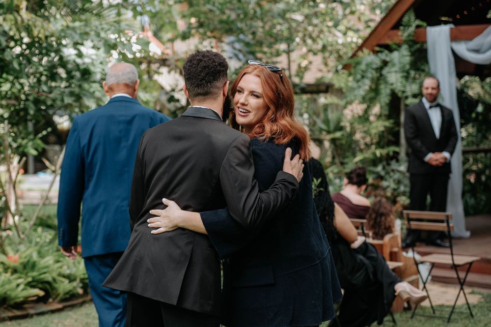 Two people share a warm embrace during an outdoor garden wedding ceremony.