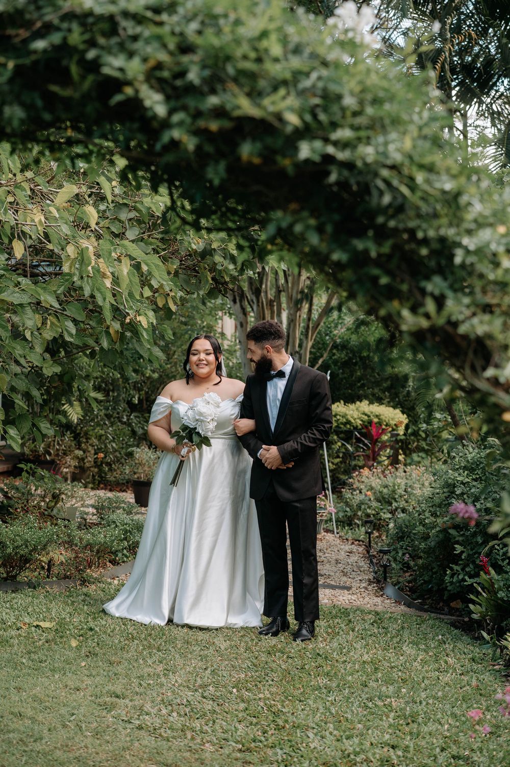 Newlywed couple shares a joyful moment together in a lush garden setting surrounded by greenery.