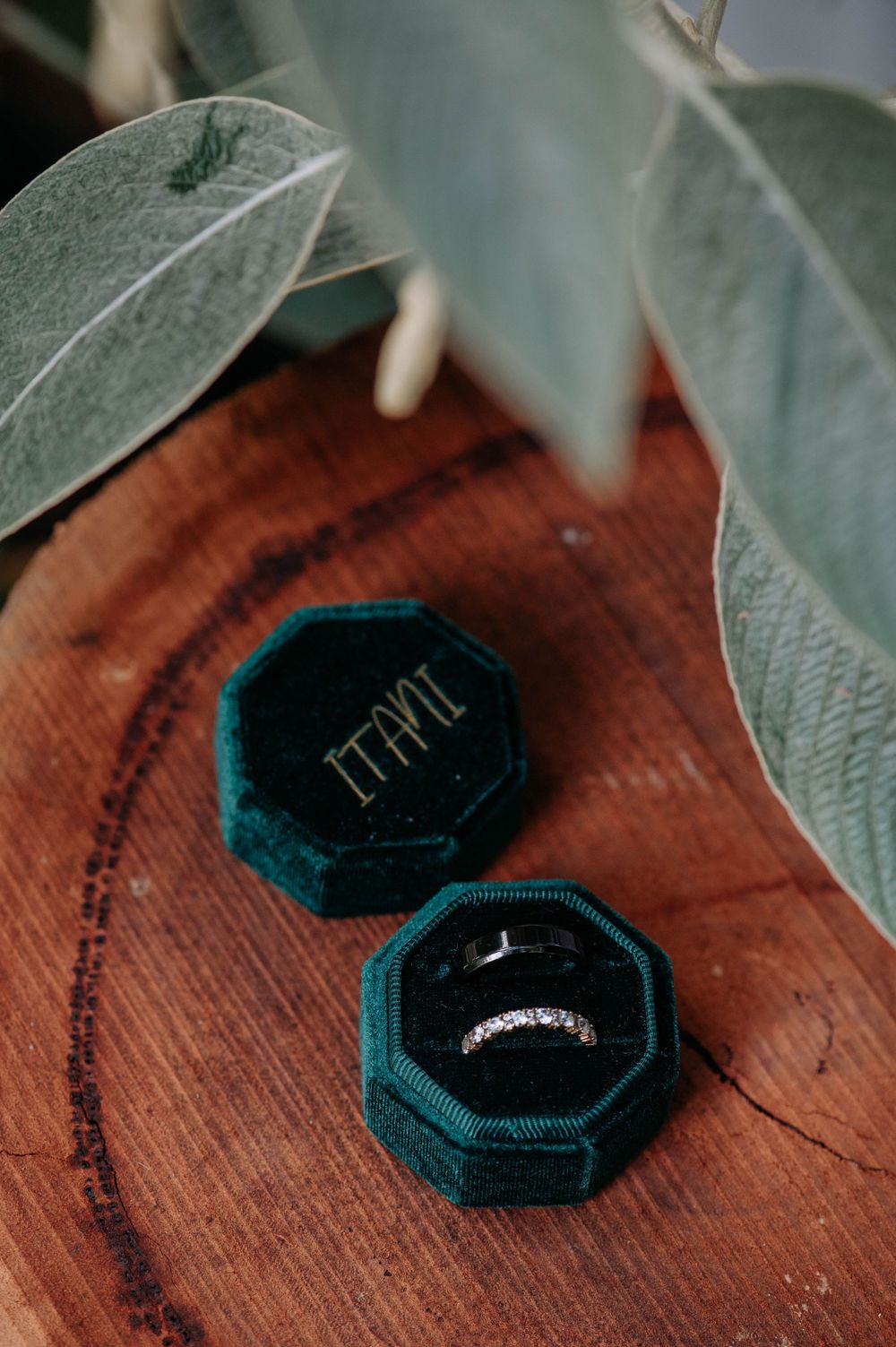 Series of elegant dark green velvet ring boxes with diamond engagement rings displayed on rustic wooden surface.