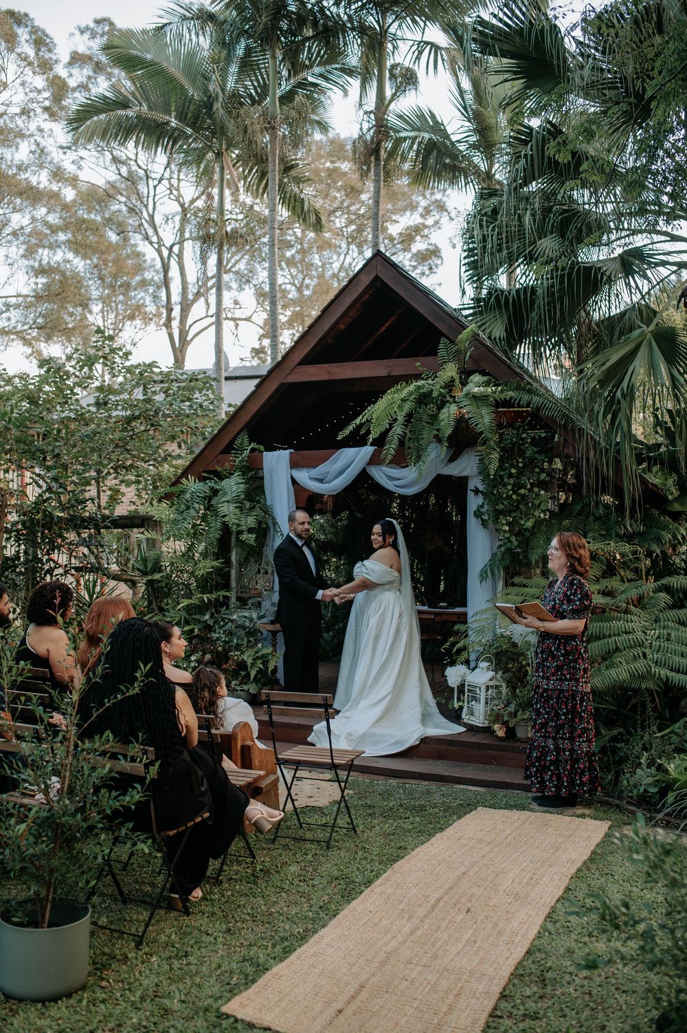 A sequence of photos showing people preparing and arranging fabric decor in a tropical garden wedding setting.