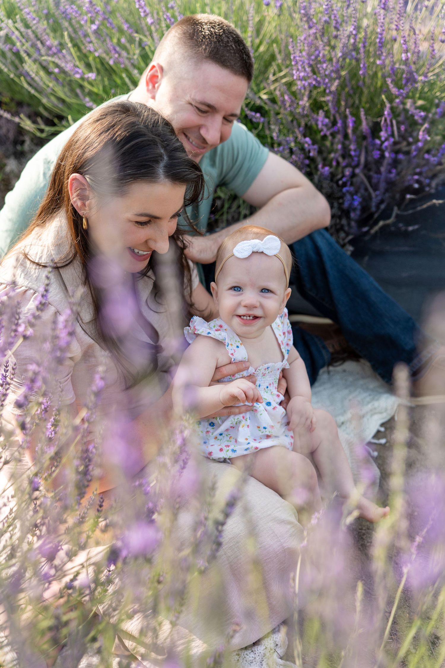 A family shares tender moments among blooming purple lavender flowers in a dreamy outdoor setting.