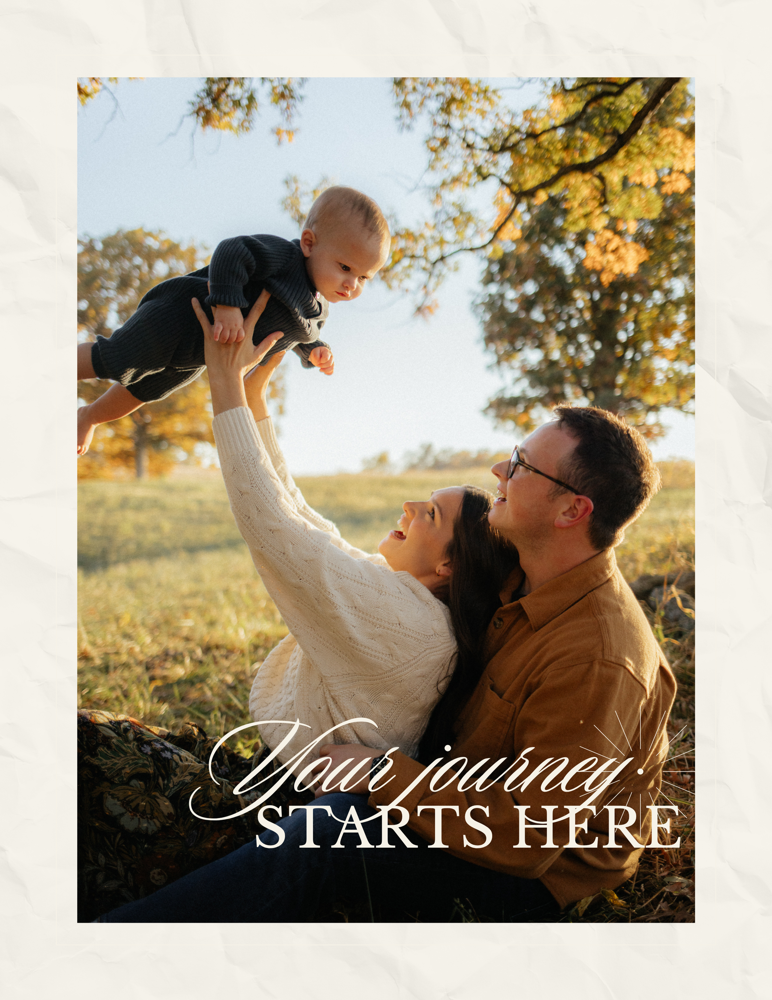 A tender family moment captured at sunset in a golden field with autumn trees in the background.