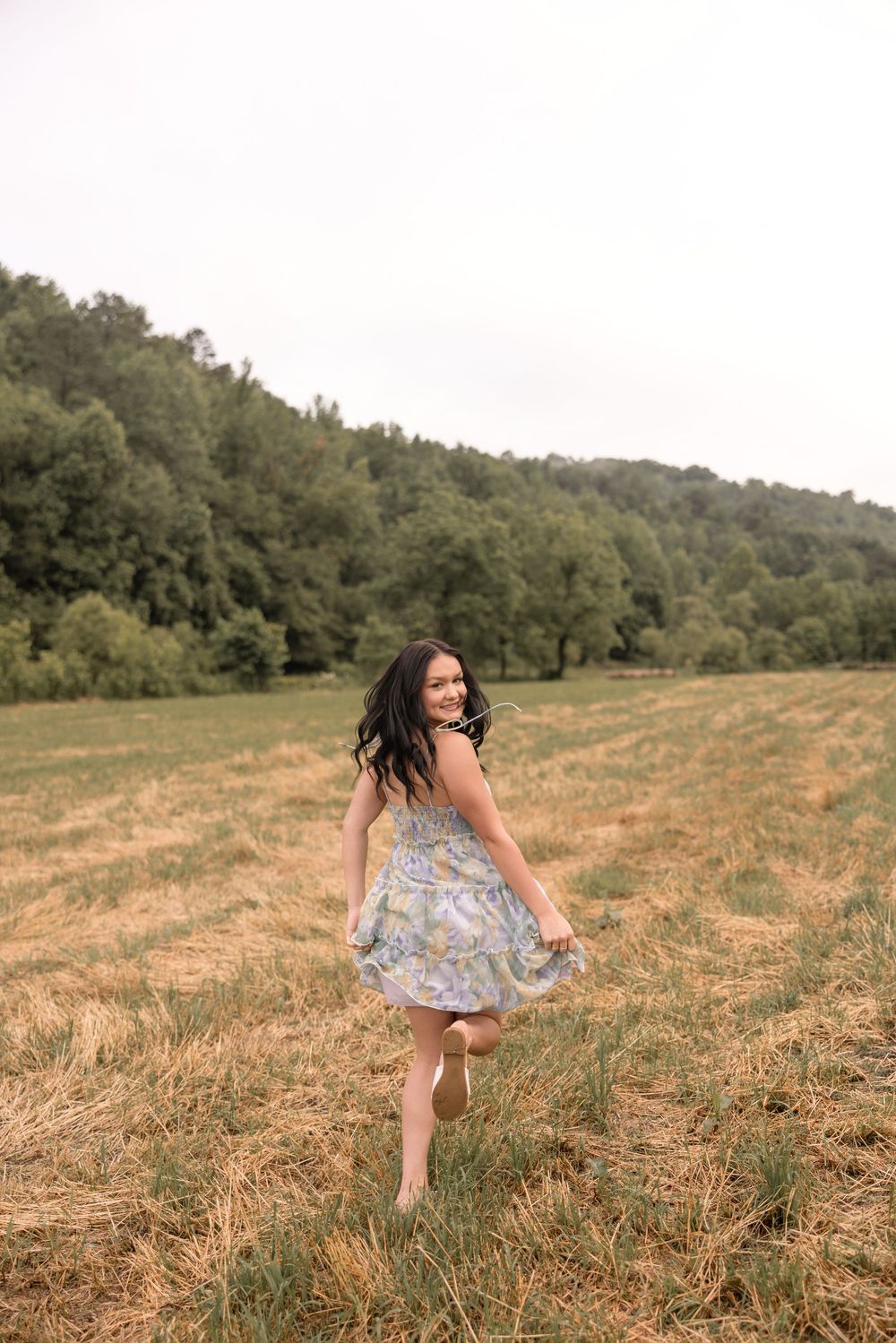 A person in a flowy dress runs joyfully through a golden hay field on a summer afternoon.