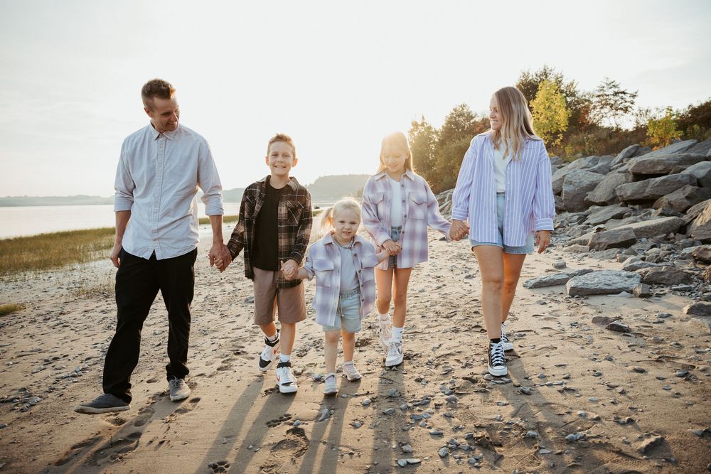 Family walking together along a rocky beach shoreline at sunset.