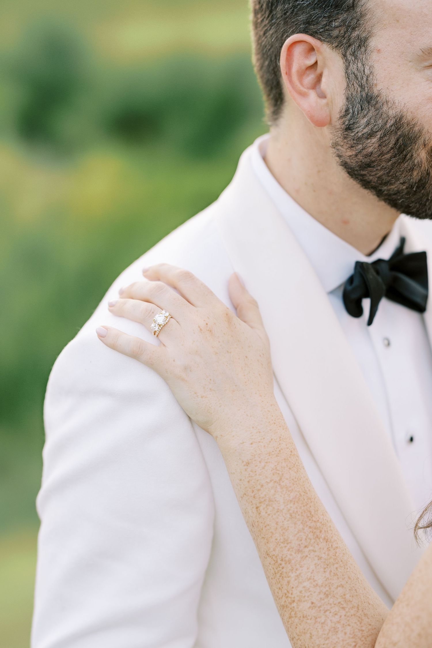 Close-up view of elegant black bow tie being adjusted against crisp white tuxedo shirt.