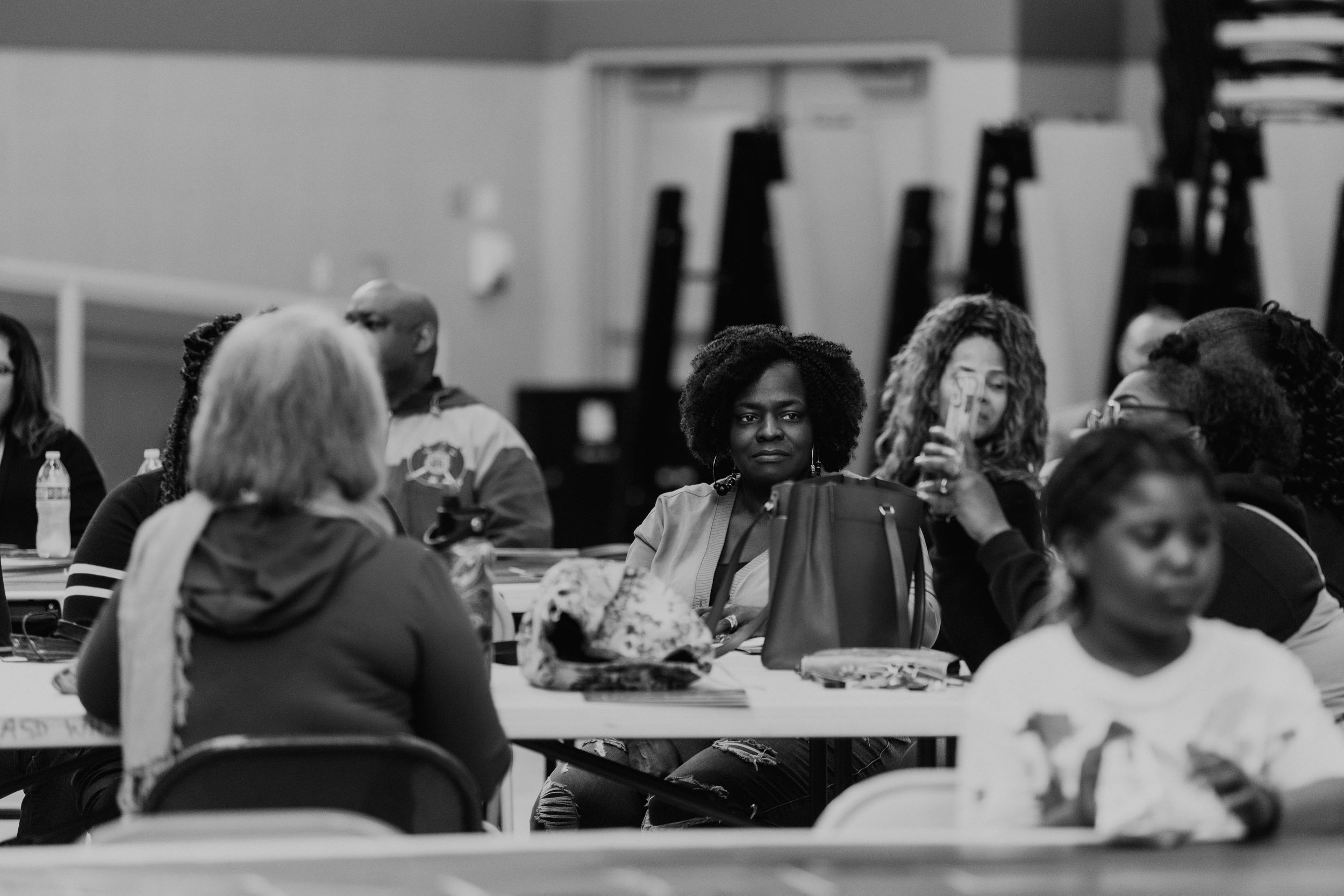 People gathered around tables in a community meeting or dining hall setting.