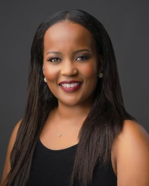 Professional headshot portrait of a woman in black attire smiling warmly against a dark background.