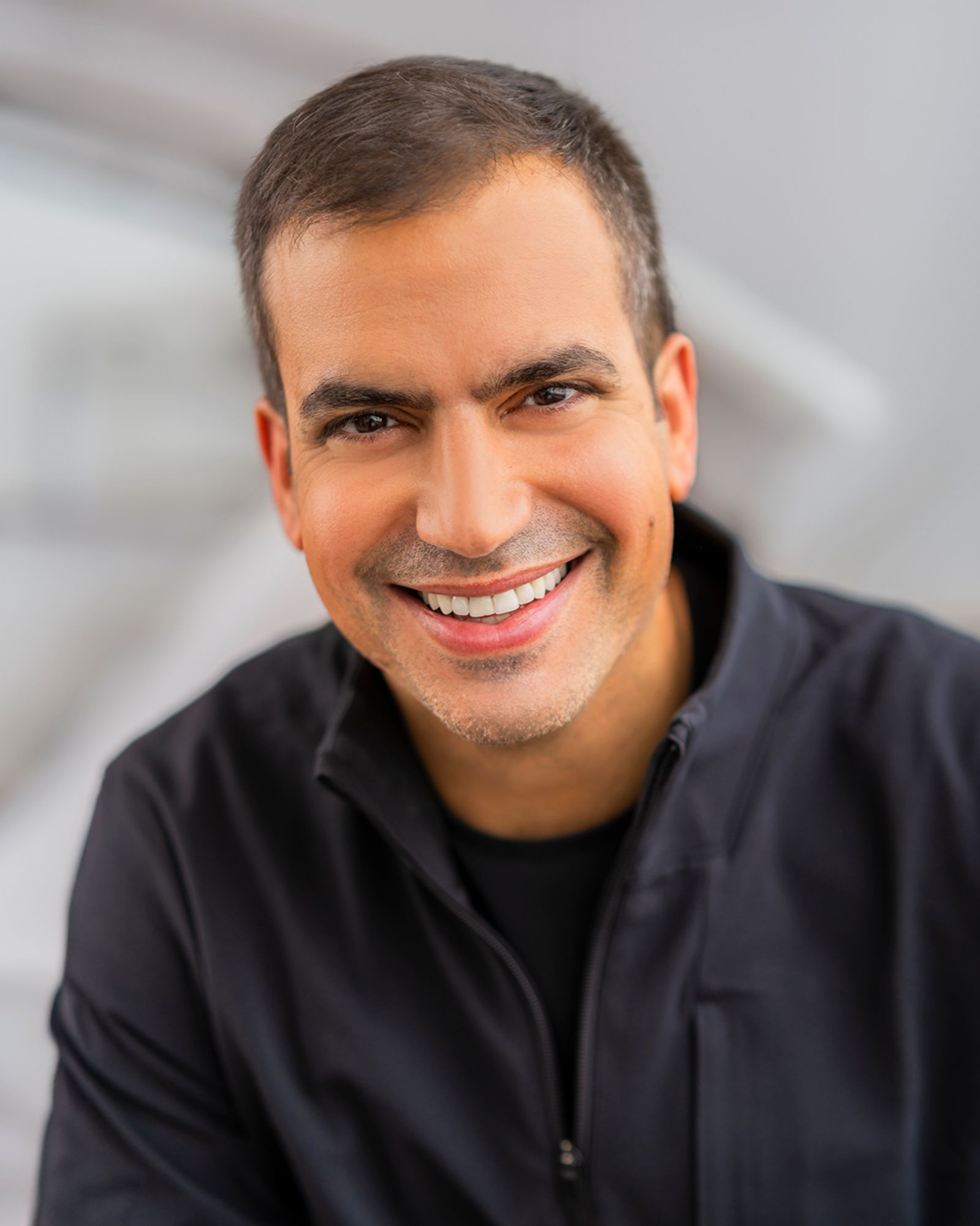 Professional headshot portraits showing warm smiles and casual black attire against light gray background.