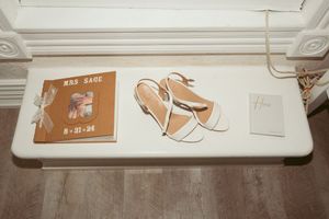 White surface displaying a vintage record album and elegant beige high-heeled sandals.