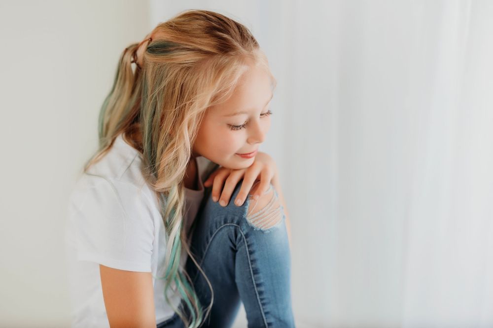 Young person in denim and white tee shows natural expressions in minimalist studio setting.