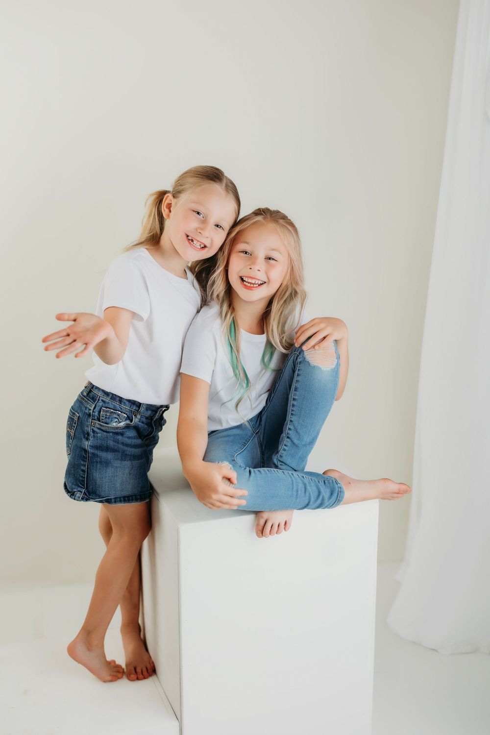 Two people share a joyful moment while sitting and standing by a white cube.