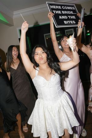 A sequence of party photos showing someone in a white dress holding up fun wedding signs at a reception celebration.