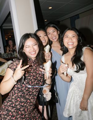 A group of friends laughing and posing with frozen treats at an indoor gathering.