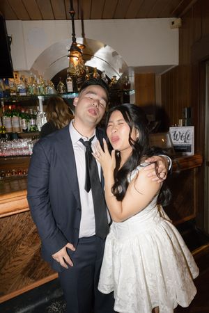 A couple in formal attire having fun and posing playfully at a bar or reception venue.