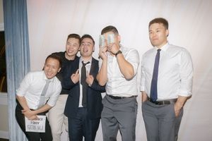 Groomsmen in formal attire posing playfully together at a wedding celebration.