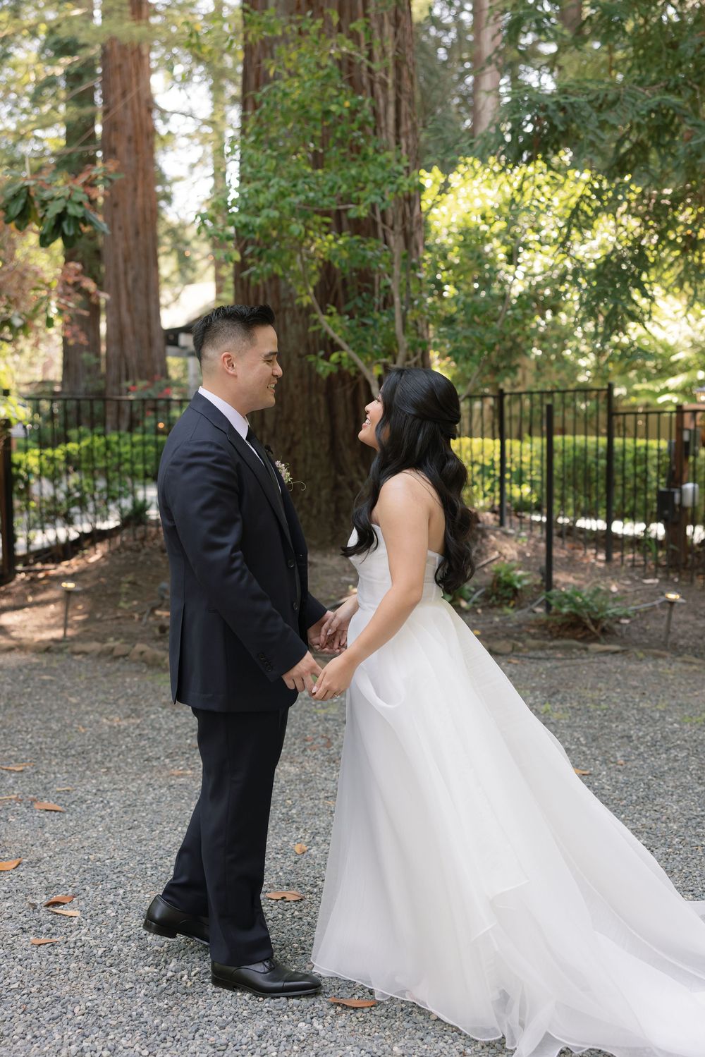 A couple shares an intimate moment among redwood trees during their wedding photo session.