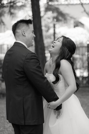 A wedding couple shares a joyful moment while laughing and embracing during their outdoor photo session.