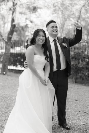 A happy couple celebrates their wedding day in an outdoor setting wearing traditional black and white formal attire.