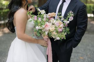 A gentle kiss shared by the elegant bride and groom outdoors with soft pink florals in the bouquet.