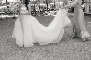 Black and white photograph of wedding party walking outdoors in flowing white dresses.