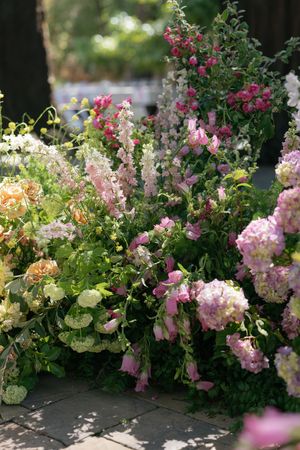 Beautiful cottage garden border filled with pink roses, delicate foxgloves and hydrangeas blooming in soft summer light.