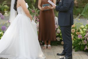 A happy couple poses in a garden during their wedding ceremony surrounded by blooming flowers and greenery.