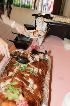 Slicing and serving roasted whole turkey garnished with fresh herbs on aluminum foil at a dinner gathering.