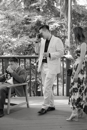 A couple performs a sequence of romantic dips during outdoor dance steps on a patio in black and white photography.
