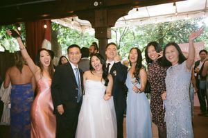Wedding party guests posing together at an indoor reception venue with decorative lighting.