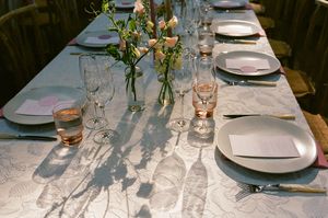 An elegant table setting with wine glasses, white plates, and fresh floral centerpieces extending down a long dining table.