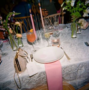 An elegant table setting with linen tablecloth, pink napkins, glassware and floral centerpieces at a formal dinner party.
