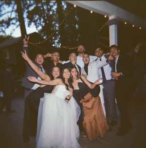 Wedding party members striking fun poses together during an evening celebration.