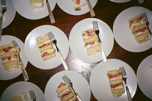 Multiple white plates with sliced sandwich portions arranged on a dark wooden table surface.