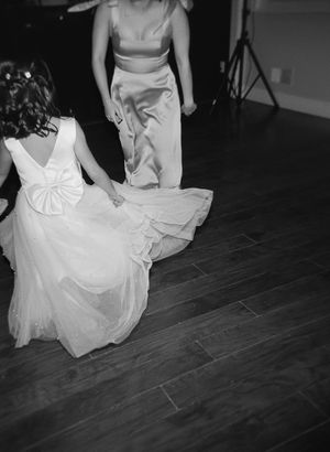 Ethereal black and white photo of flowing white wedding dresses on a dark wooden floor.