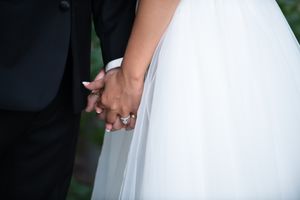 Close-up shot of bride and groom holding hands with their wedding rings during a ceremony.