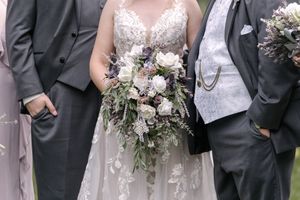 Wedding party gathers together in elegant gray and white attire while holding beautiful floral bouquets.
