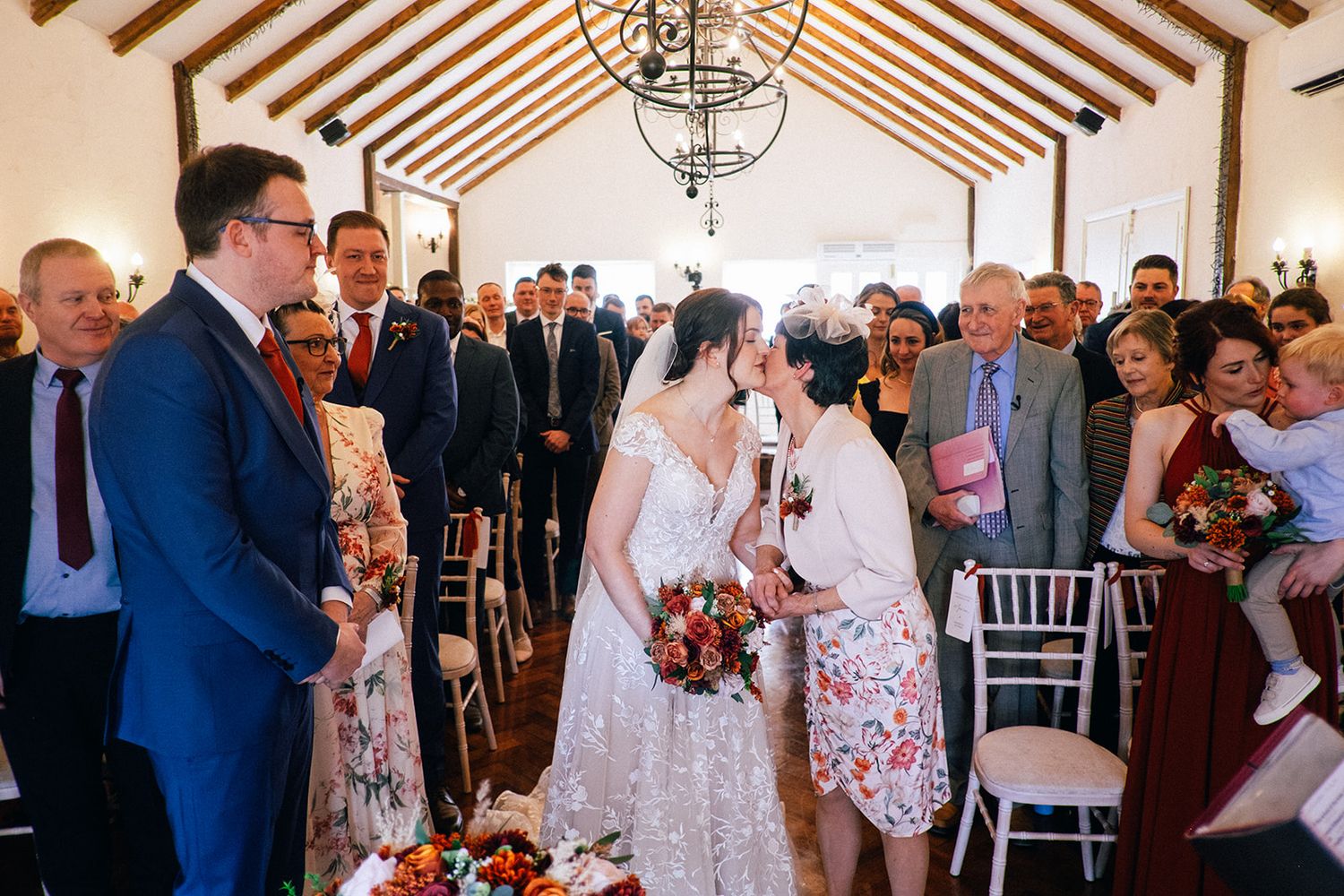 Crondon Park Wedding Ceremony - Guests gather in a rustic venue with wooden beamed ceilings during a celebration.