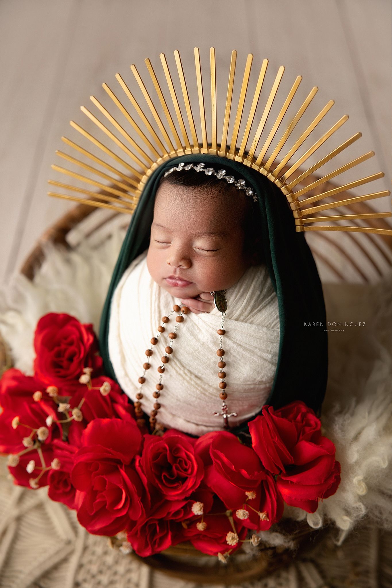 Sleeping newborn wearing red headband rests peacefully on plush red pillow against crimson background.