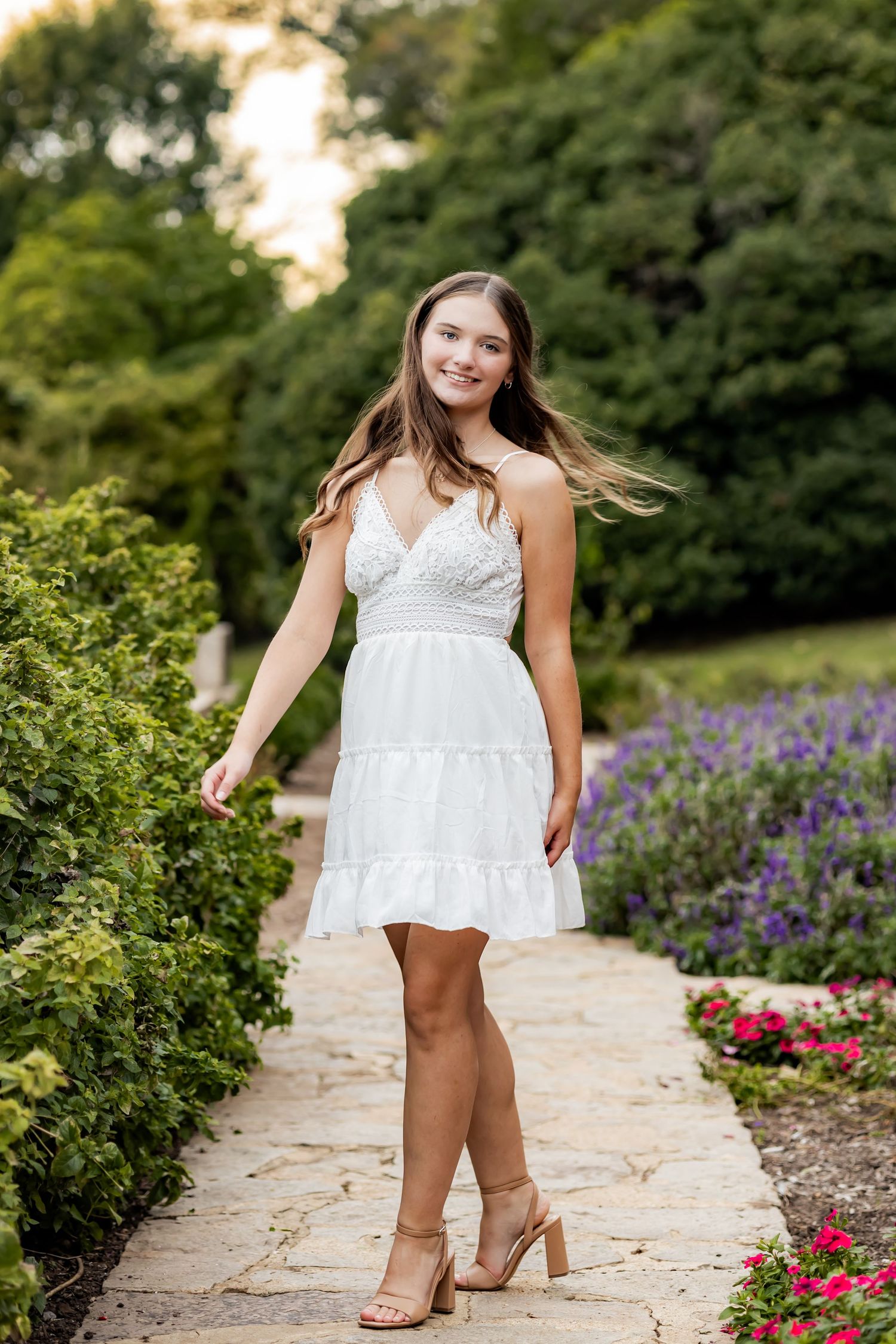 A series of playful photos taken on a garden path surrounded by purple and pink flowers and green shrubs. HS Senior photographer in RVA