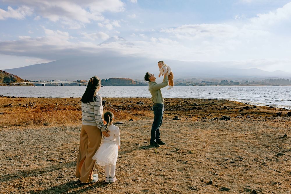 Family spending time together on a rocky beach shore with mountains and ocean views in the background.
