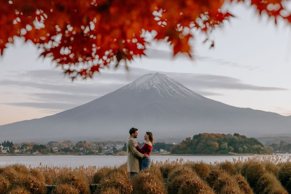 Panoramic view of Mount Fuji with red autumn maple leaves and lake reflection in Japan.
